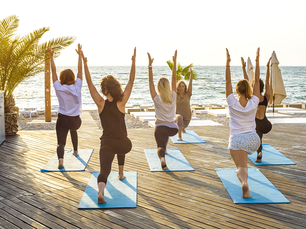 Group yoga exercise by the beach during sunset